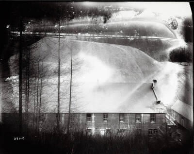 Image of a large building against the hillside (may be mine waste) at the Success Mine property. Image is overexposed.