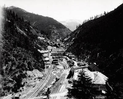 A distant view of the town of Burke, Idaho and building of Hecla Mine; a railroad track can be seen going into town.
