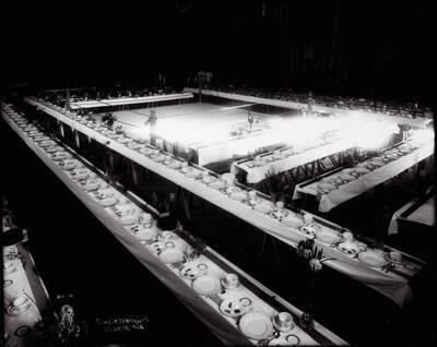 Interior view of the Eagles hall in Wallace, Idaho. Banquet tables are set and a group of wait staff is in the background. Caption on back: "F.O.E. Eagles Banquet tables March 11,1914." Caption on front: "Eagle Banquet. Mar. 11, 1914"