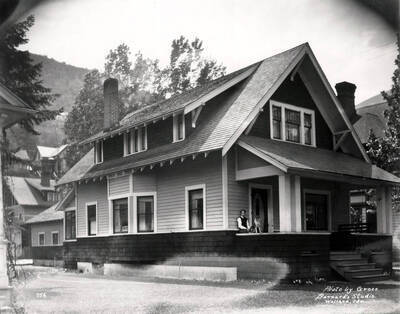 314 Cedar Street, Wallace, ID. Image shows a boy and dog sitting on the porch of Charles E. Inskip's house in Wallace, Idaho, May 1925; photo is taken by Gross for Barnard's Studio. Charles E. Inskip was the partner of "Inskip & English Plumbing & Heating Co." in Wallace.