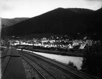 Showing soldiers tents, up against a river and railroad tracks
