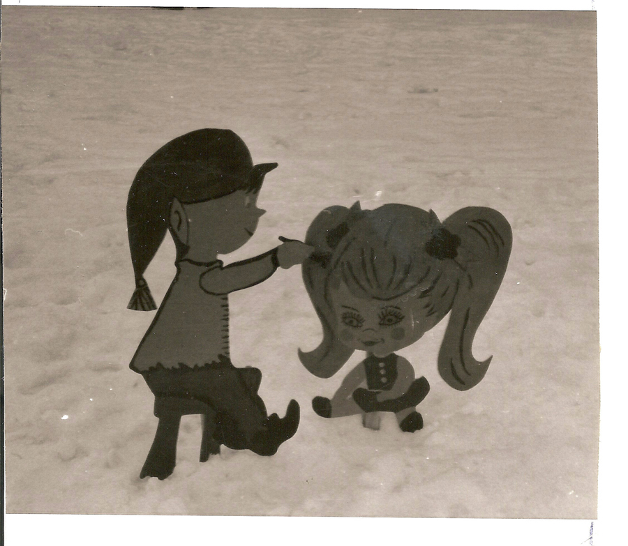 Two cartoon-style figures in a snowy setting. One figure, with a long ponytail and hat, is sitting and appears to be combing the hair of another figure with large pigtails. The larger figure has a face with exaggerated features, including big eyes and a small mouth. Both are stylized with simple features.