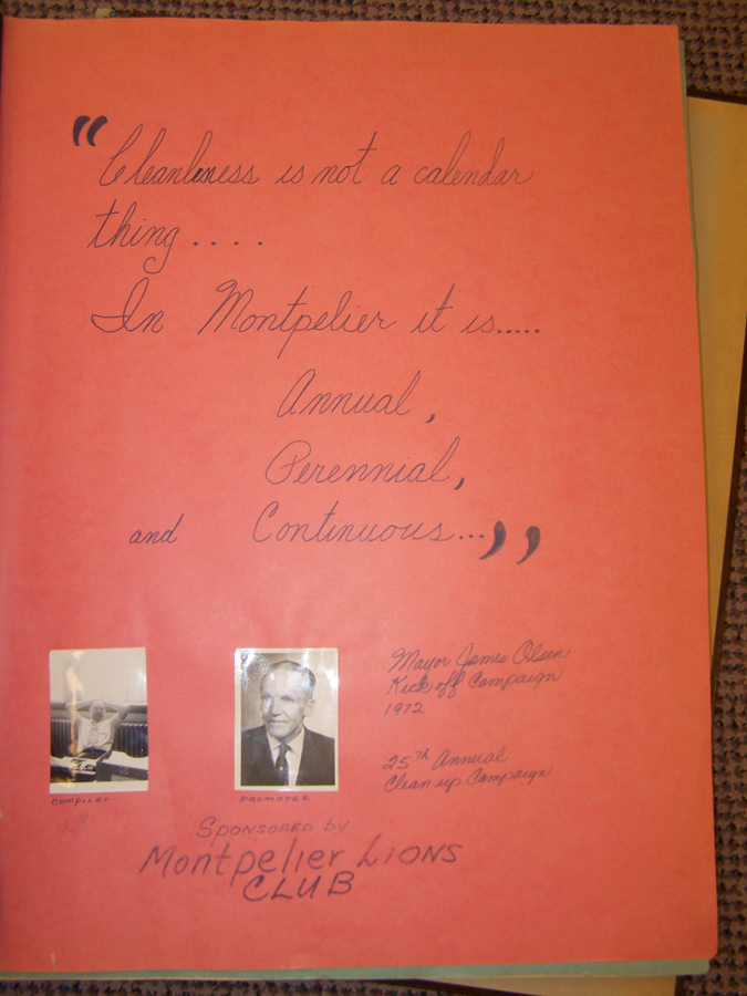 An orange sheet with a handwritten quote that says, "Cleanliness is not a calendar thing.... In Montpelier it is.... Annual, Perennial, and Continuous..." Below the quote are two black-and-white photographs labeled "compiler" and "promoter." To the right, handwritten text notes "Mayor James Olsen Kick off Campaign 1972" and "25th Annual Clean up Campaign." The bottom text reads, "Sponsored by Montpelier Lions Club."