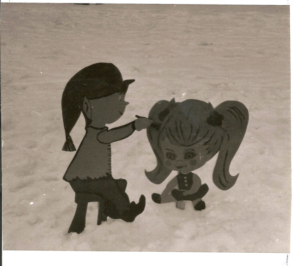 Two cartoon-style figures in a snowy setting. One figure, with a long ponytail and hat, is sitting and appears to be combing the hair of another figure with large pigtails. The larger figure has a face with exaggerated features, including big eyes and a small mouth. Both are stylized with simple features.