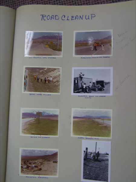 A scrapbook page titled "Road Cleanup" with eight photographs arranged in two columns. The top left photograph shows a road with the description "All traffic was stopped." Next to it, a photo with people standing by the road labeled "Flag girls explaining program." Below are images of people by a hill tagged "Bags were filled" and people near a truck marked "Dumped bags to larger units." Middle row has a photo of a landscape with a sign, described as "After the cleanup," and a road image labeled "Clean shoulder view." The bottom row includes a photograph of scattered materials tagged "Collected materials" and a person by a fence. Handwritten names are noted on the right side.