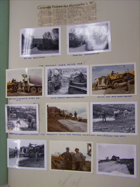 A collage of seven photographs depicting various stages of construction work and equipment with handwritten captions. At the top, a newspaper clipping titled "Concrete Poured for Montpelier's 'M'." The captions below the images read: "In the Beginning," "Partial Completion," "Bear Lake Concrete Mixed the Mix," "City Crews Transferred Mix," "Using Cat and Dump Bucket," "Montpelier Construction Worked the Product into the Proper Locations and Leveled the Mix." There are two men posing in one image, and several construction vehicles and workers are visible in others. Handwritten notes are visible next to some photos.