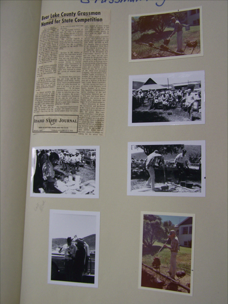 A newspaper clipping with the headline "Bear Lake County Grassman Named for State Competition" is attached to a page. The text below is labeled "IDAHO STATE JOURNAL" with the date "Thursday, November 2, 1972." Beside the clipping, six photographs are displayed. The images show various outdoor scenes with people involved in activities such as cooking over an open flame, carrying items in a group, and interacting near vehicles. A house and trees are visible in the background of some images. There is handwriting at the top saying "Grassman."