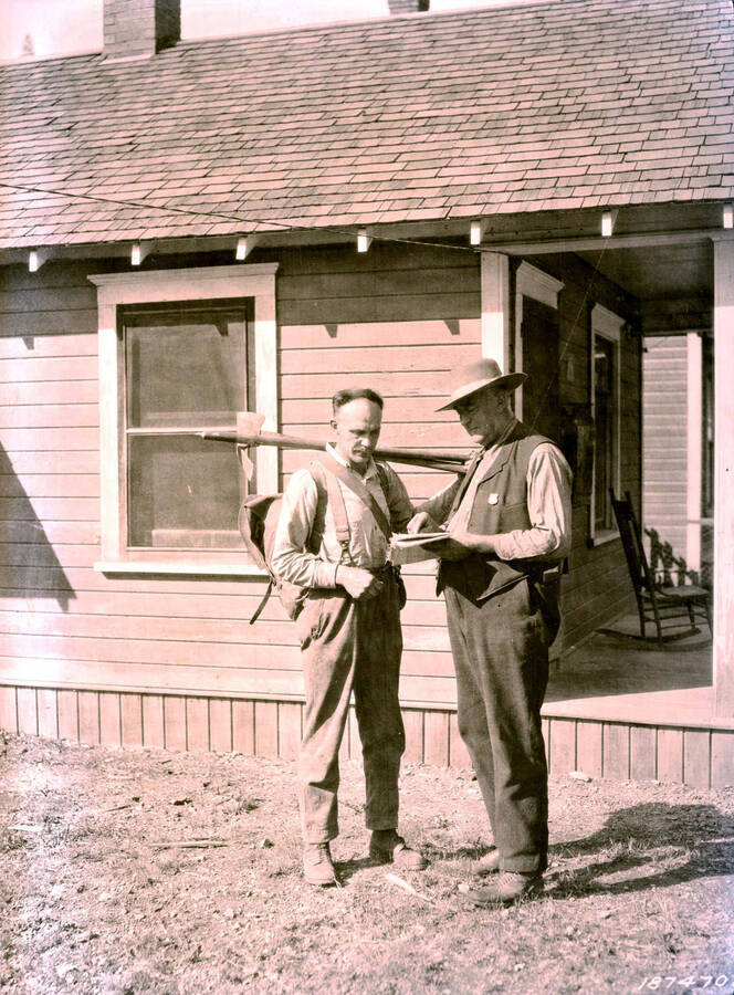 Images shows two men standing in the yard of a home. 1910 Forest fire