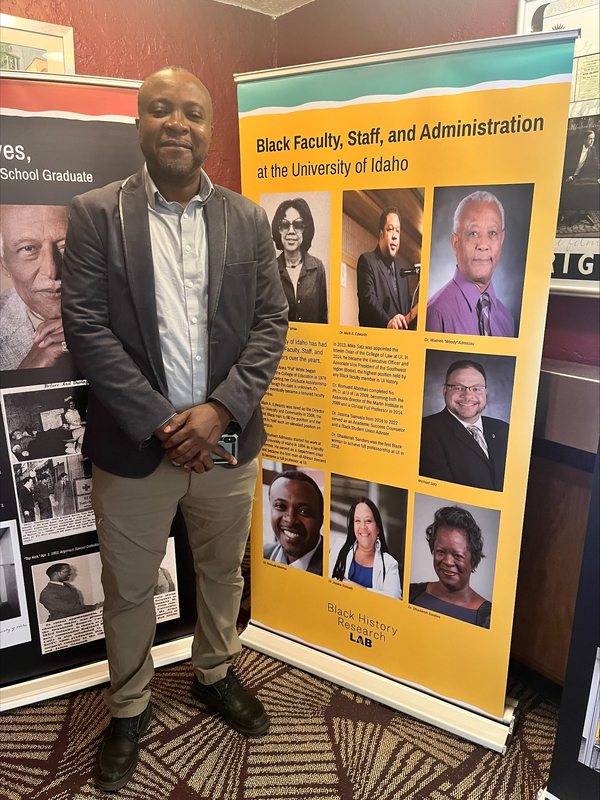 Dr. Romuald K. Afatchao standing near Black History Research Lab banners inside the Kenworthy Theatre.