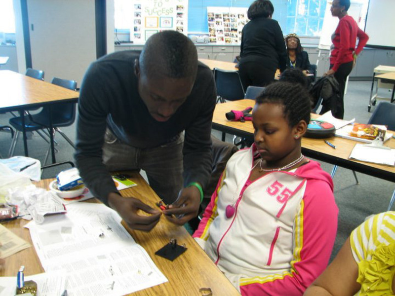 Mouhamado Diop helps student with an activity 
 at an engineering outreach event in 2010