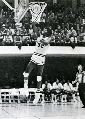 Chris Price, mid jump. A referee, other players, and the crowd can be seen in the background.