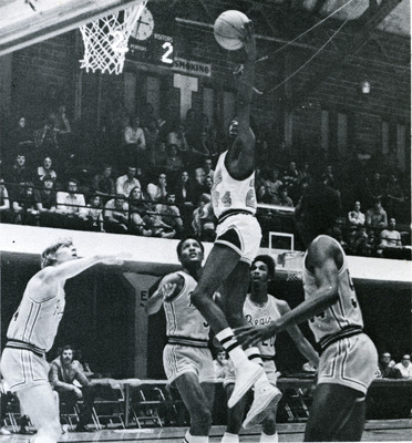 Chris Mcguire, mid jump. Four other players surround Mcguire, as the crowd watches in the background.