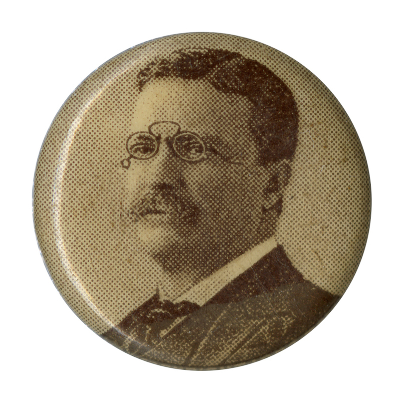 Round, off-white button with a black and white portrait of Theodore Roosevelt at the center. 