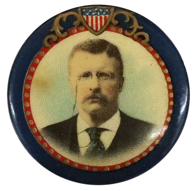 Round, white button bordered by blue and red with a crest, with a color portrait of Theodore Roosevelt. 