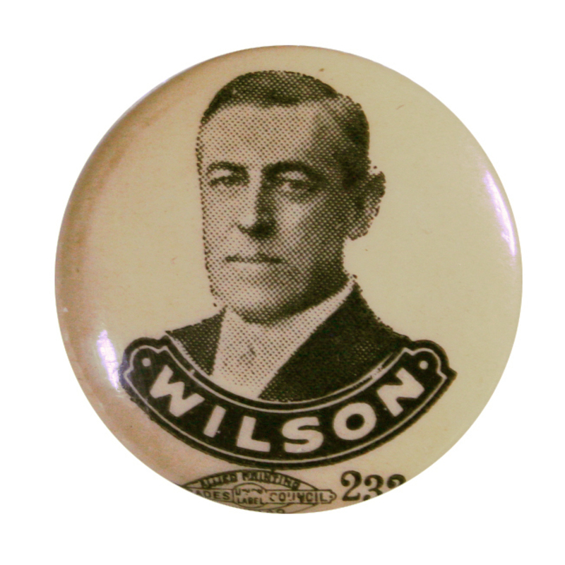 Round, white button with a black and white portrait of Woodrow Wilson, with bold white text reading "Wilson" within a bordered box at the bottom. 