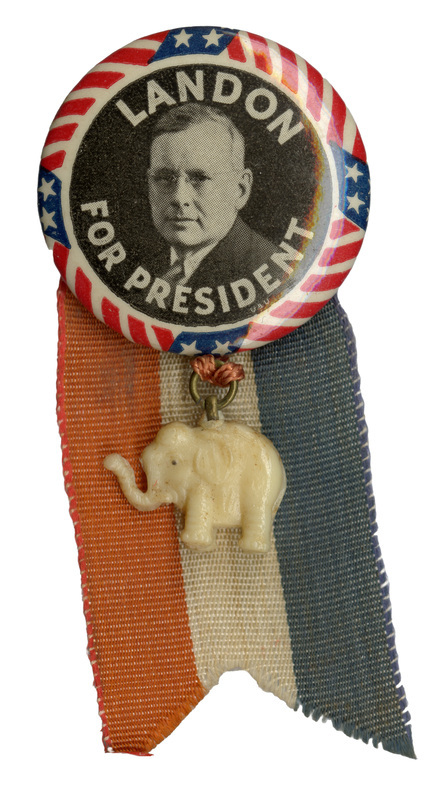 Round button with a black and white portrait of Alfred Landon, encircled by a US flag border. White text reads "Landon for President".  Attached below the button is a red, white, and blue ribbon and a white elephant charm. 