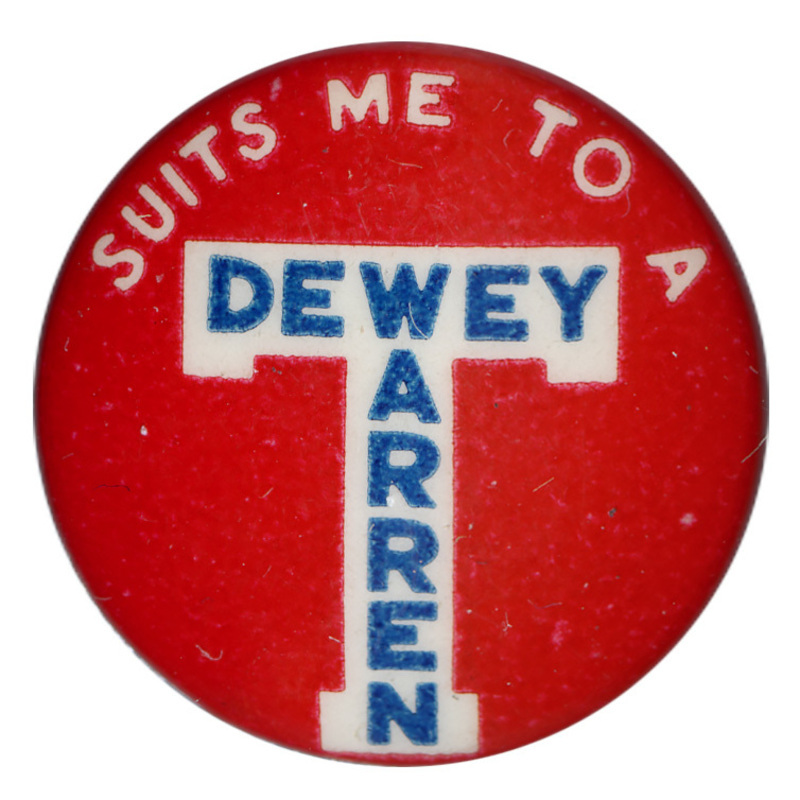 Round, red button with a white, decorative letter "T". White and blue text reads "Suits me to a T Dewey Warren". 