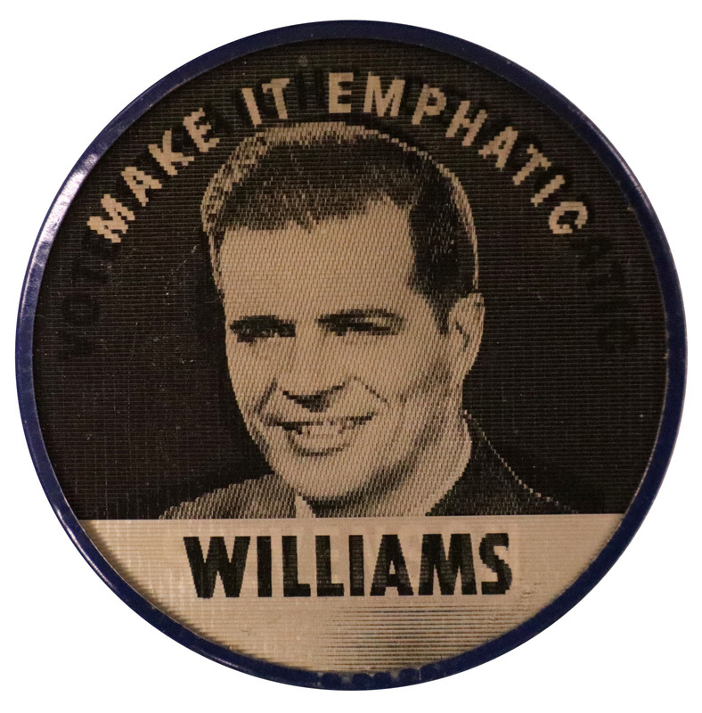 Round, black and white button with a photograph of G. Mennen Williams and the text "Make it Emphatic, Williams." This is one angle of a holographic button.