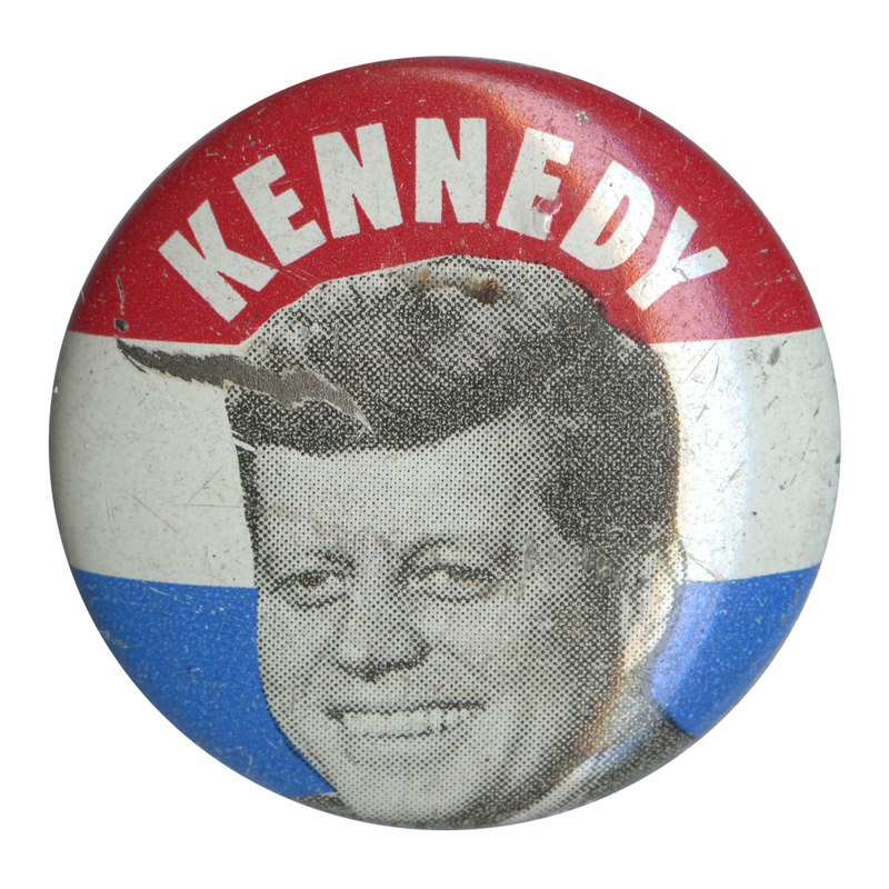 Round button with three horizontal stripes of red, white, and blue. A grayscale portrait of John F. Kennedy at the center. White text reads "Kennedy" at the top.  