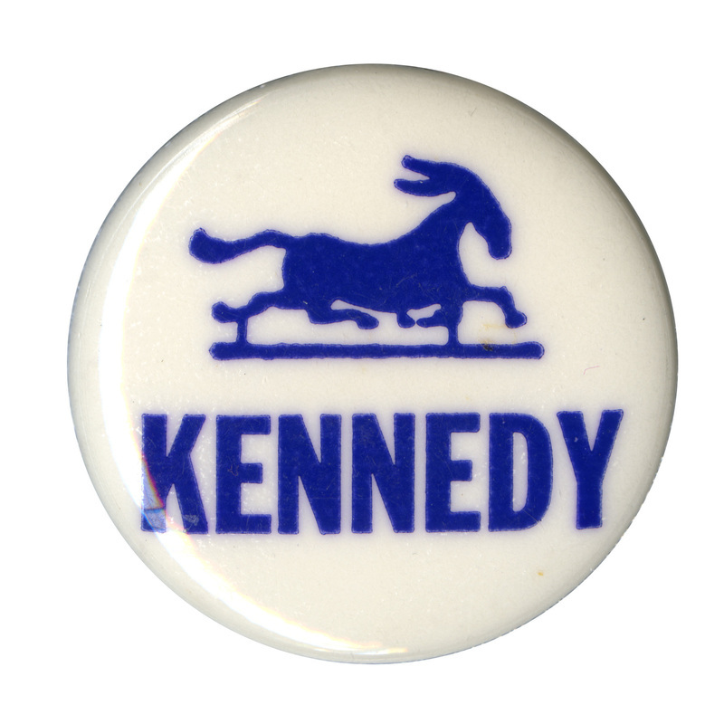 Round, white button with a blue silhouette of a running donkey. Blue text reads "Kennedy" below. 