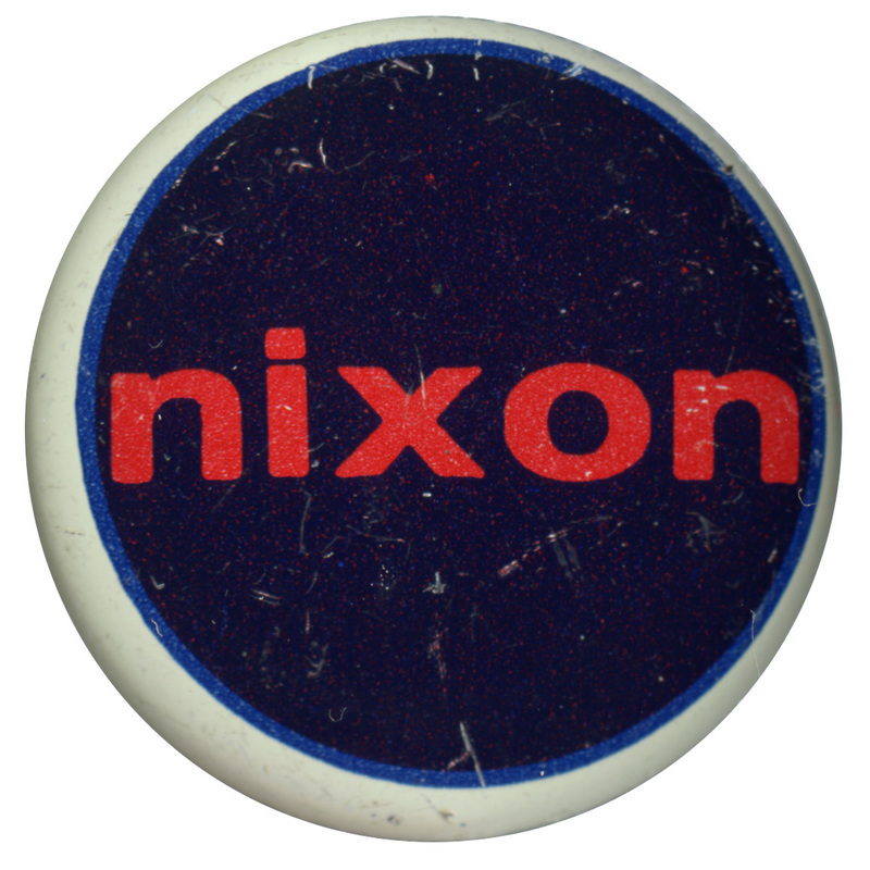 Round, dark blue button with a white border. Red text reads "nixon" at the center. 