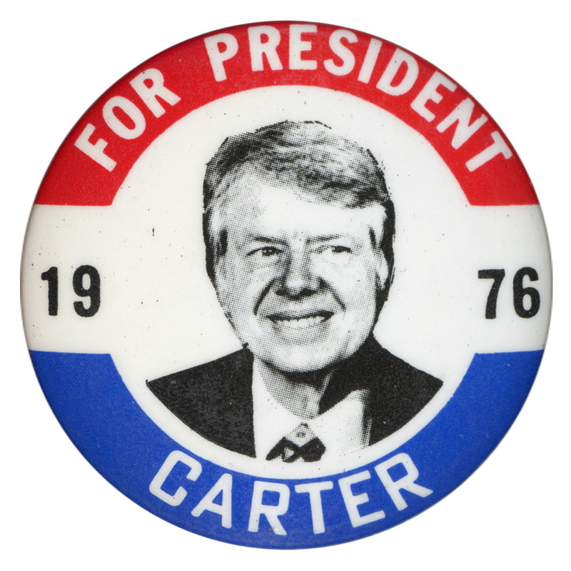 Round, white button with red and blue bands along the edge and a black and white portrait of Jimmy Carter. White and black text reads "FOR PRESIDENT 1976 CARTER"