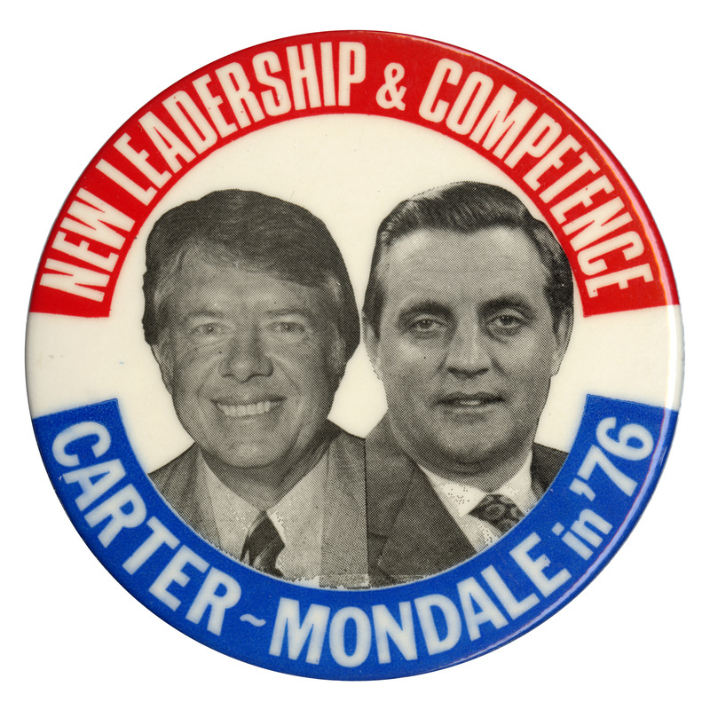 Round, white button with red and blue bands along the edge and black and white portraits of Jimmy Carter and Walter Mondale. White text reads "NEW LEADERSHIP & COMPETENCE CARTER-MONDALE"
