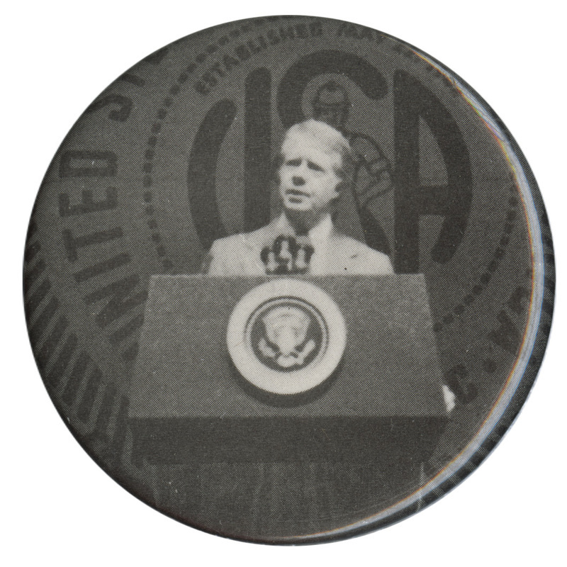 Round button with a black and white photograph of Jimmy Carter speaking at a podium.