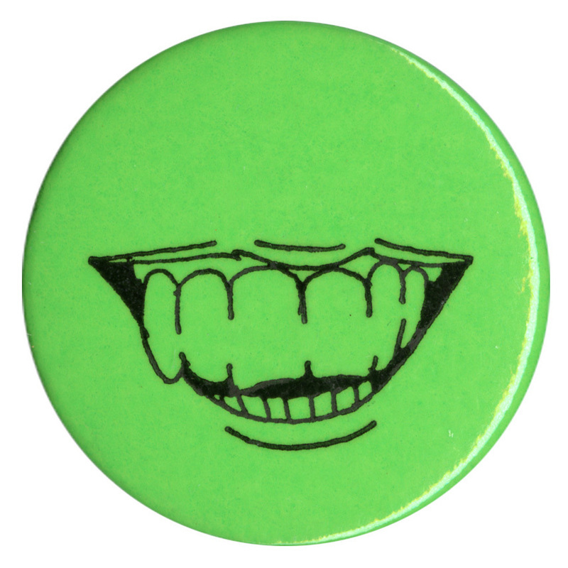 Round, green button with a black drawing of a toothy mouth smiling.