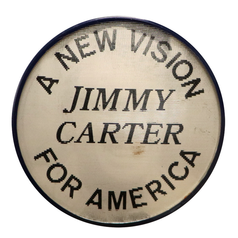Round, black and white button with a photograph of Jimmy Carter. This is one angle of a holographic button.