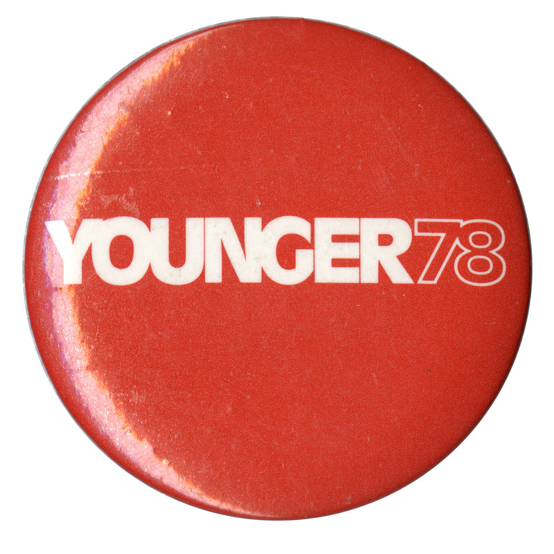 Round, red button with white text reading "YOUNGER 78"