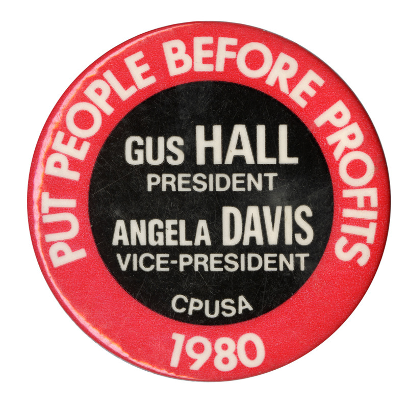 Round, red button with a black circle in the middle. White text reads "PUT PEOPLE BEFORE PROFITS GUS HALL PRESIDENT ANGELA DAVIS VICE-PRESIDENT CPUSA 1980"