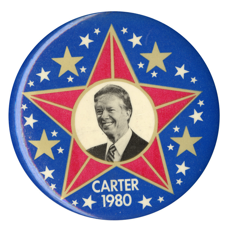 Round, blue button with gold, red, and white star decorations and a black and white photograph of Jimmy Carter in the center. White text reads "CARTER 1980"
