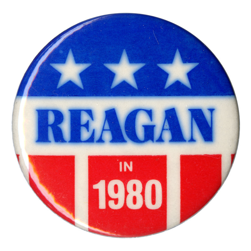 Round button with blue and red stars and stripes decorations. Blue and white text reads "REAGAN IN 1980"