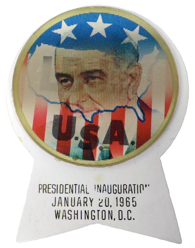 Round button with red, white, and blue flag decorations, the outline of the United States, and a color portrait of Lyndon B. Johnson. Text reads "LBJ for the USA." This is one angle of a holographic button. A white, ribbon-shaped piece of plastic is attached to the button and contains the text "Presidential Inauguration January 20, 1965 Washington, D.C."