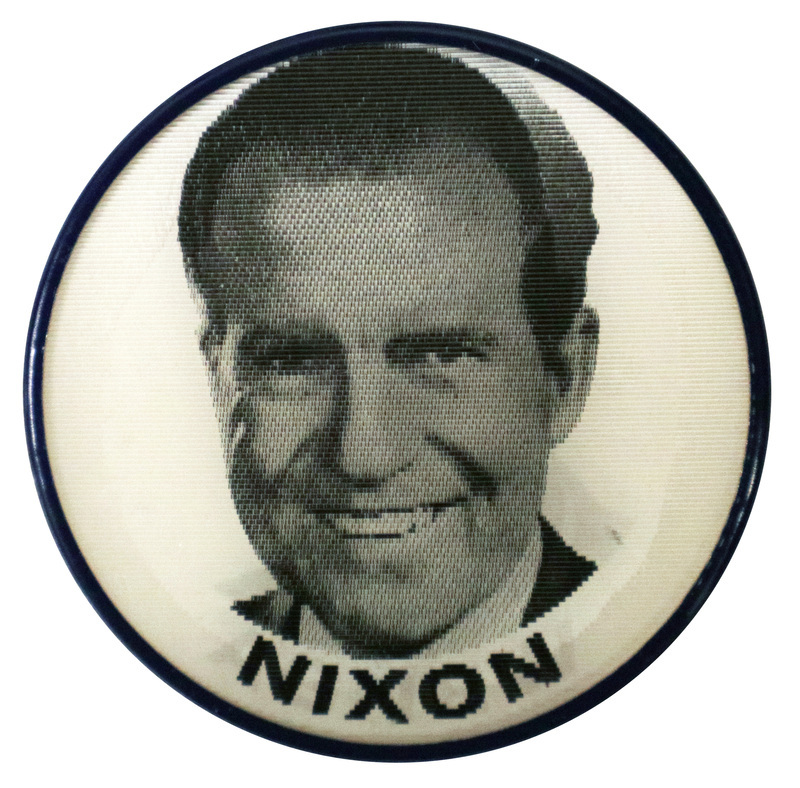 Round, white button with a portrait of RIchard Nixon and black text reading "Nixon." This is one angle of a holographic button.
