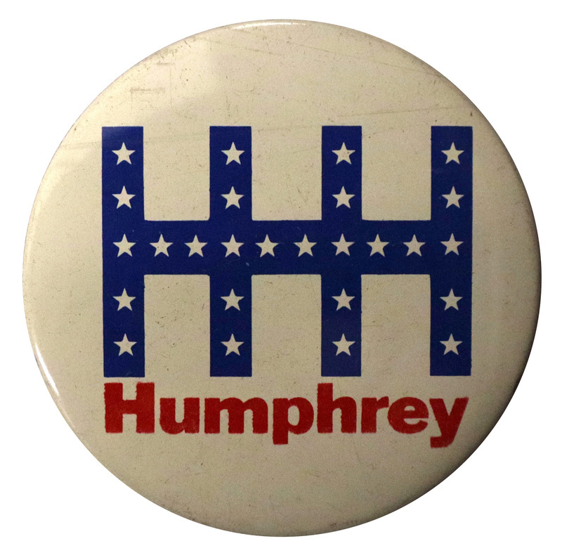 Round, white button with a stylized "HHH" composed of blue bands and white stars. Red text underneath reads "Humphrey."