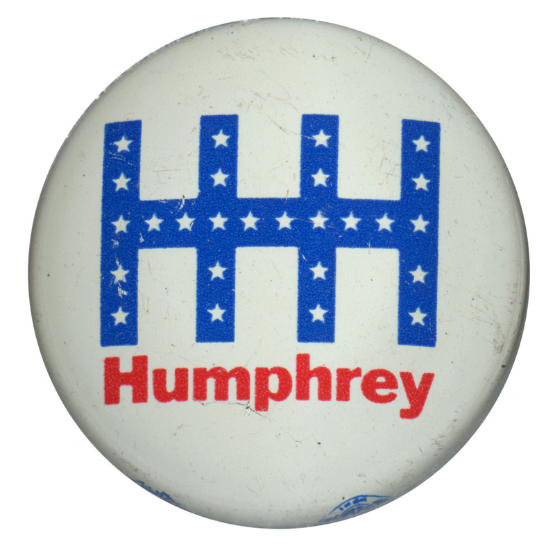 Round, white button with a stylized "HHH" composed of blue bands and white stars. Red text underneath reads "Humphrey."