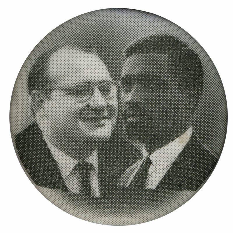 Round, black and white button with portraits of Fred Halstead and Paul Boutelle.