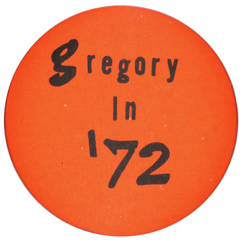 Round, orange button with black text reading "Gregory in '72."