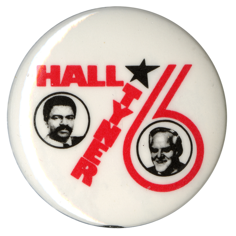 Round, white button with black and white portraits of Gus Hall and Jarvis Tyner. Red text and a black star form the number "76." The text reads "Hall Tyner."