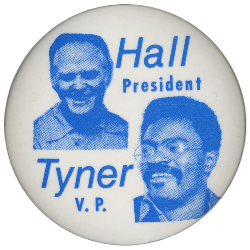 Round, white button with blue portraits of Gus Hall and Jarvis Tyner. Blue text reads "Hall President, Tyner V. P."