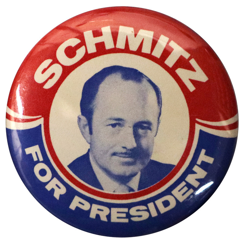 Round, red, white, and blue button with a portrait of John Schmitz. White text reads "SCHMITZ FOR PRESIDENT"