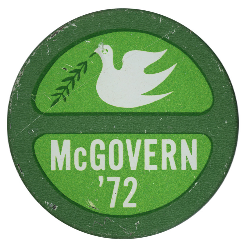 Round, green button with a drawing of a white dove with a peace sign on its head, holding a darker green olive branch. White text in the bottom half reads "McGOVERN '72"