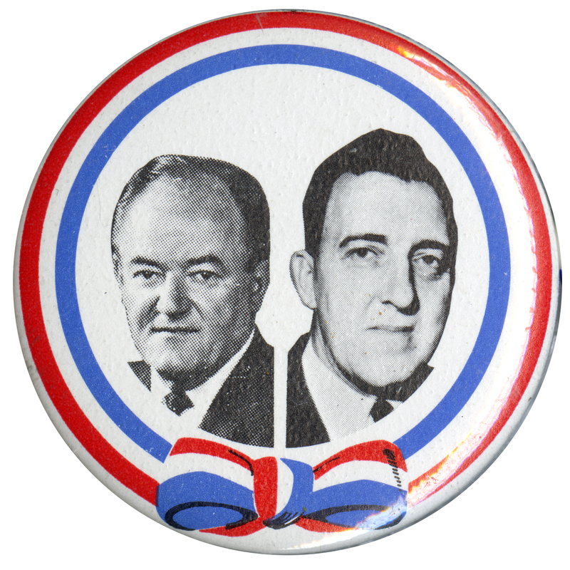 Round, white button edged in red and blue stripes. Black and white portraits of Hubert Humphrey and Edmund Muskie.