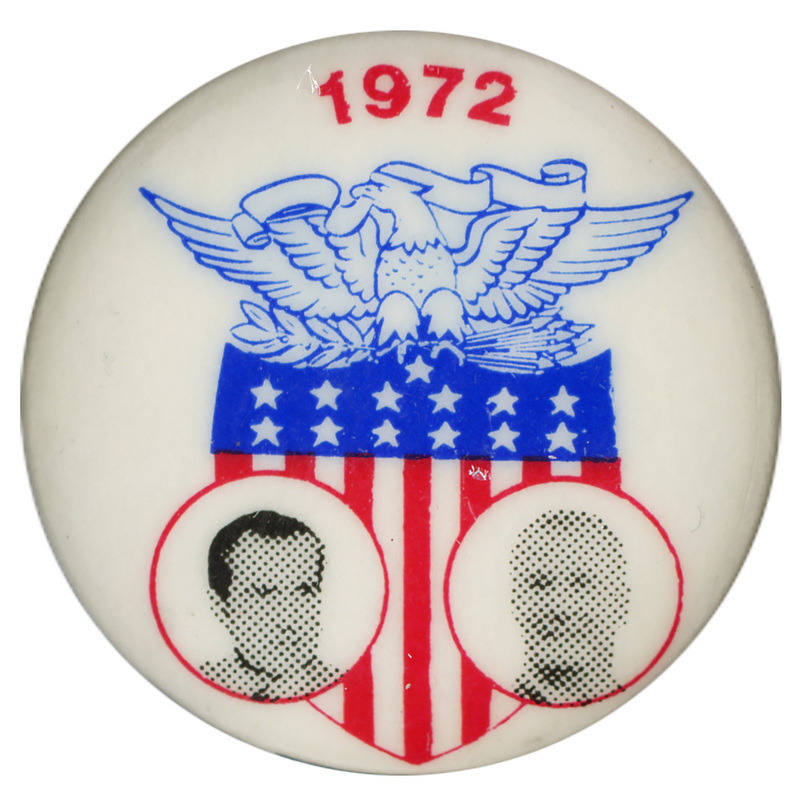 Round, white button with black and white portraits of Richard Nixon and Spiro Agnew against a red and blue shield topped by an eagle. Red text reads "1972"