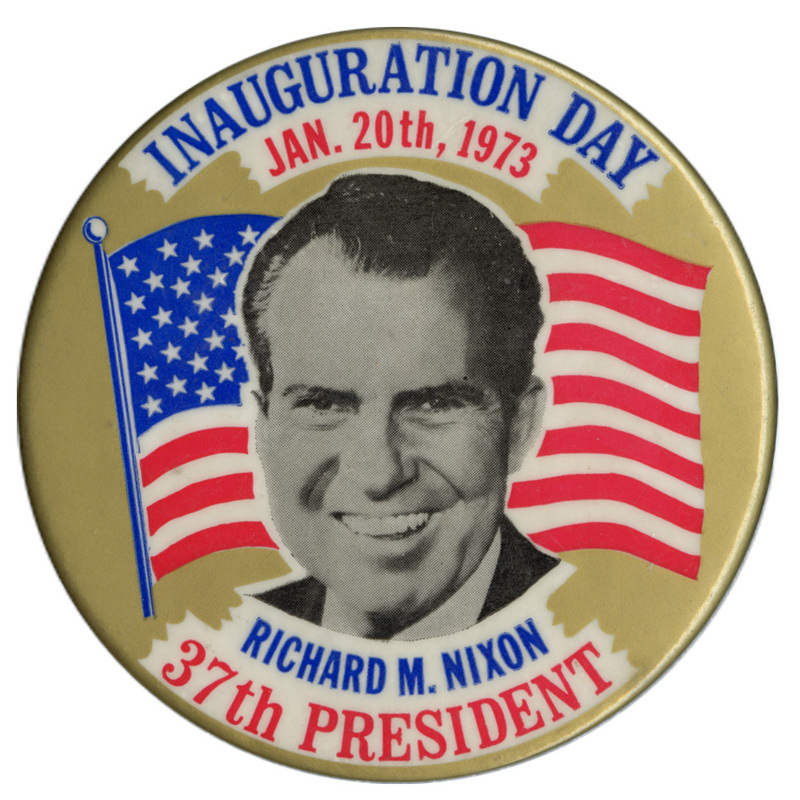 Round, gold button with a black and white portrait of Richard Nixon against a red, white, and blue US flag. Red and blue text reads "INAUGURATION DAY JAN. 20th, 1973 RICHARD M. NIXON 37th PRESIDENT"