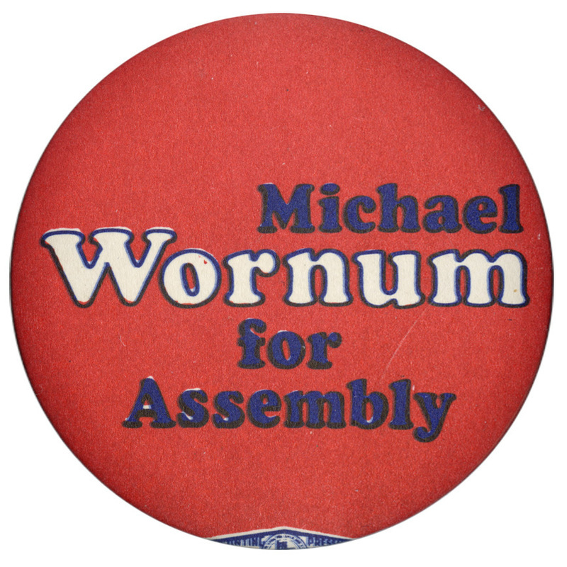 Round, red button with white and black text reading "Michael Wornum for Assembly"