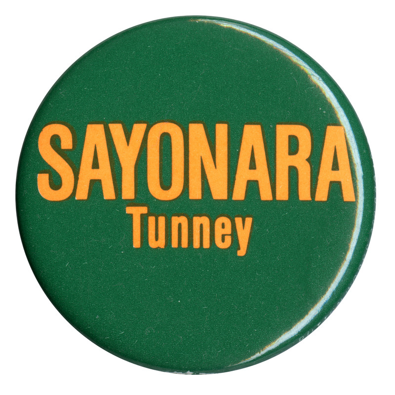 Round, dark green button with yellow text reading "SAYONARA Tunney"