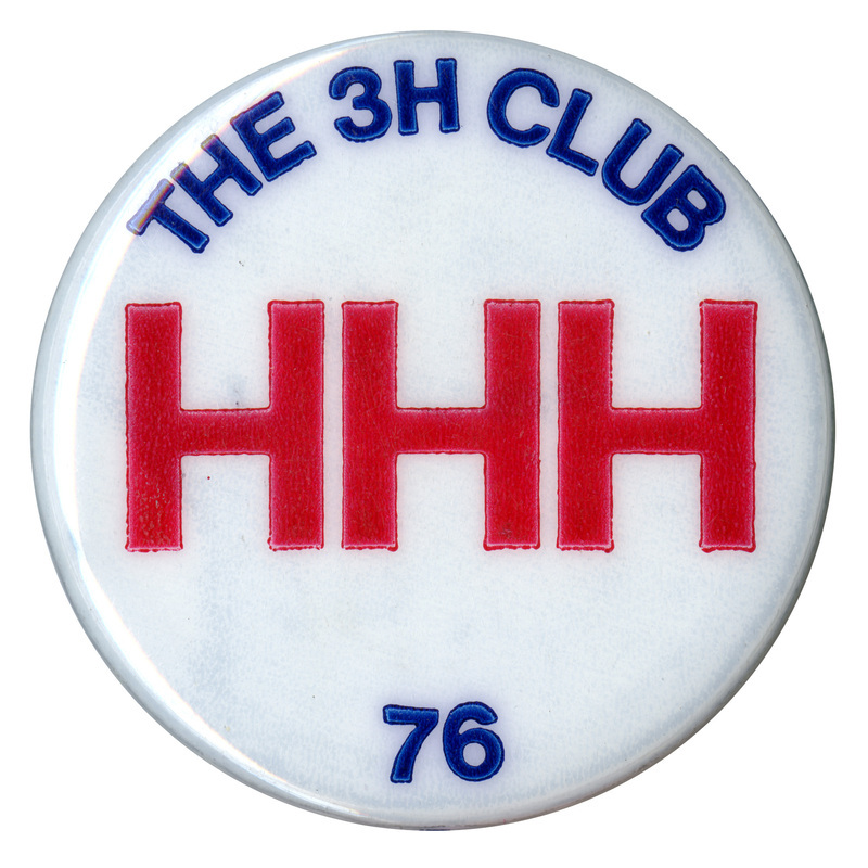 Round, white button with blue and red text reading "THE 3H CLUB HHH 76"
